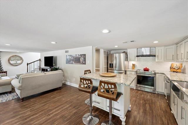 3231 Charles Ave, Groves, TX 77619 - kitchen with appliances with stainless steel finishes, open floor plan, a kitchen island, light stone countertops, and recessed lighting