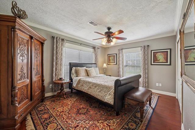 3231 Charles Ave, Groves, TX 77619 - bedroom with ornamental molding, a textured ceiling, dark wood finished floors, and ceiling fan
