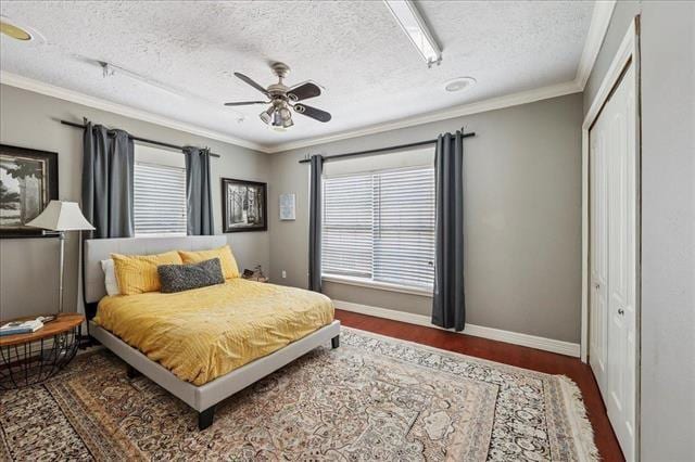3231 Charles Ave, Groves, TX 77619 - bedroom featuring wood finished floors, crown molding, a closet, a textured ceiling, and a ceiling fan