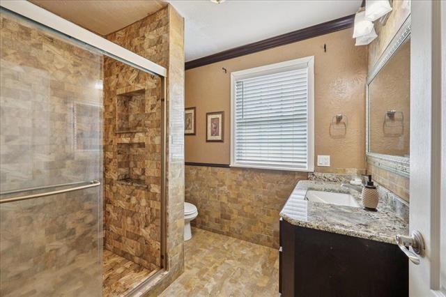 3231 Charles Ave, Groves, TX 77619 - full bath with vanity, ornamental molding, a stall shower, tile walls, and a wainscoted wall