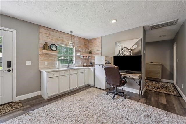 3231 Charles Ave, Groves, TX 77619 - office area featuring wood finished floors, a textured ceiling, and wood walls