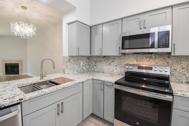 7677 Cambridge St, Houston, TX 77054 - kitchen with stainless steel appliances, gray cabinetry, tasteful backsplash, and a chandelier