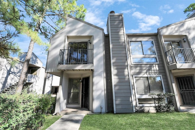 17202 Imperial Valley Dr Unit 3, Houston, TX 77060 - view of front facade featuring a balcony, a chimney, and a front lawn