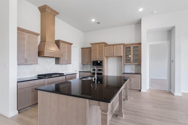 2348 Blue Sail Dr, Katy, TX 77493 - kitchen featuring built in microwave, cooktop, custom exhaust hood, light wood finished floors, and tasteful backsplash