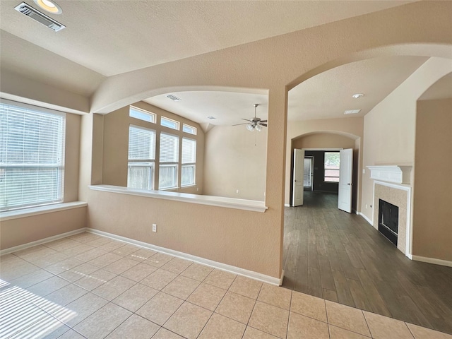 4315 Wellington Grove Ln, Katy, TX 77494 - unfurnished room featuring a ceiling fan, vaulted ceiling, arched walkways, a fireplace, and healthy amount of natural light