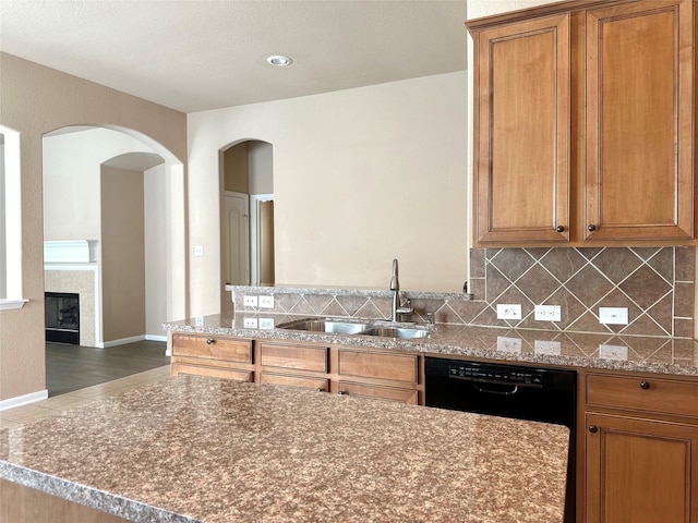 4315 Wellington Grove Ln, Katy, TX 77494 - kitchen with tasteful backsplash, brown cabinets, a peninsula, a tile fireplace, and arched walkways