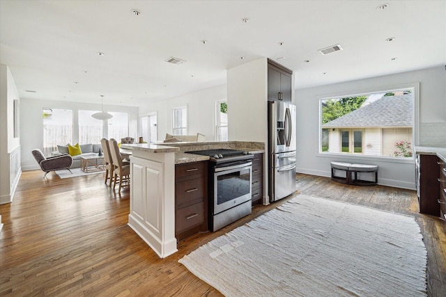 2037 Banks, Houston, TX 77098 - kitchen with appliances with stainless steel finishes, wood finished floors, dark brown cabinetry, light stone countertops, and open floor plan