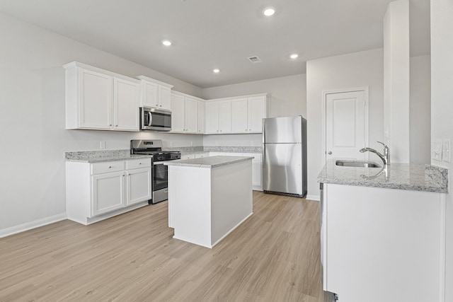 10811 Bright Beacon Dr, Beasley, TX 77417 - kitchen featuring stainless steel appliances, light wood finished floors, white cabinets, light stone countertops, and recessed lighting