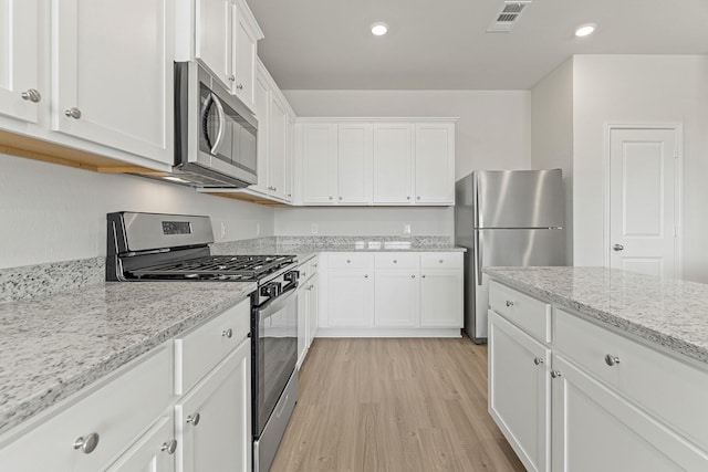 10811 Bright Beacon Dr, Beasley, TX 77417 - kitchen with appliances with stainless steel finishes, light wood-style floors, white cabinets, recessed lighting, and light stone countertops