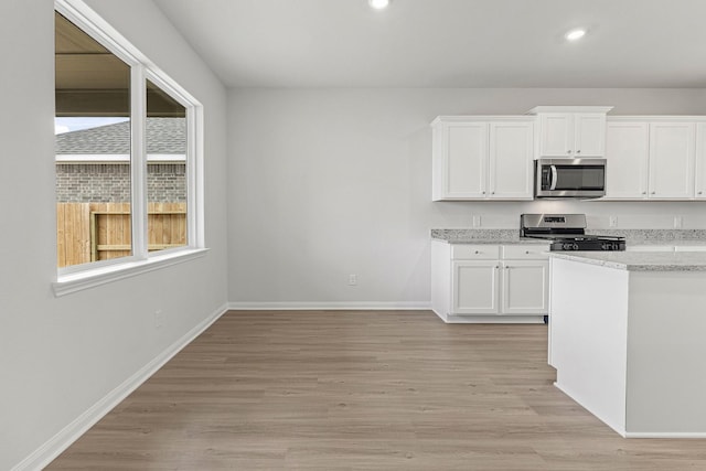 10811 Bright Beacon Dr, Beasley, TX 77417 - kitchen with stainless steel appliances, white cabinets, recessed lighting, light wood-style flooring, and light stone counters