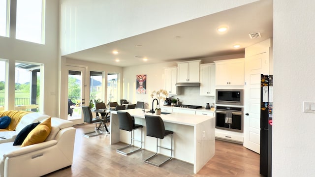 31422 Beacon Cove Trl, Fulshear, TX 77441 - kitchen featuring stainless steel appliances, open floor plan, light countertops, a kitchen breakfast bar, and white cabinets