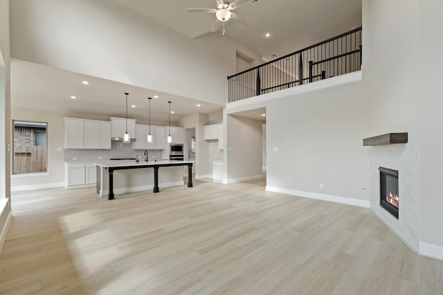 914 Hooks Trl, League City, TX 77573 - unfurnished living room with a high ceiling, ceiling fan, a fireplace, light wood-style flooring, and recessed lighting