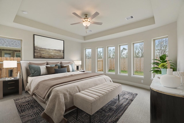 914 Hooks Trl, League City, TX 77573 - bedroom featuring a tray ceiling, light carpet, multiple windows, and ceiling fan