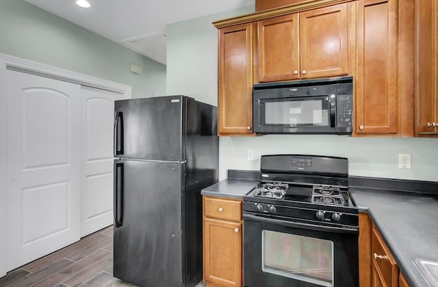 2245 Wilson St, Beaumont, TX 77703 - kitchen featuring black appliances, brown cabinets, dark wood-type flooring, dark countertops, and recessed lighting