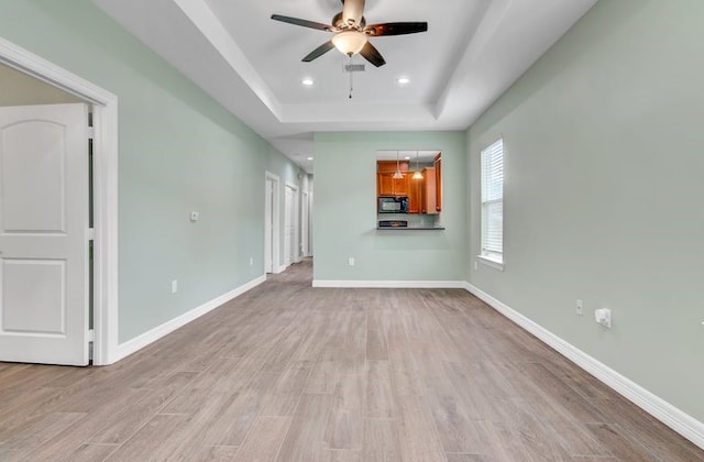 2245 Wilson St, Beaumont, TX 77703 - unfurnished living room featuring a tray ceiling, a ceiling fan, light wood-type flooring, and recessed lighting