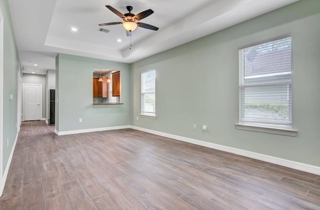 2245 Wilson St, Beaumont, TX 77703 - spare room with a tray ceiling, wood finished floors, ceiling fan, and recessed lighting