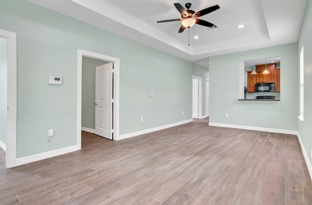2245 Wilson St, Beaumont, TX 77703 - unfurnished living room featuring a raised ceiling, a ceiling fan, light wood finished floors, and recessed lighting
