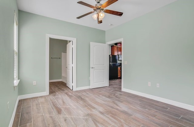 2245 Wilson St, Beaumont, TX 77703 - unfurnished bedroom with freestanding refrigerator, light wood-type flooring, a spacious closet, and a ceiling fan