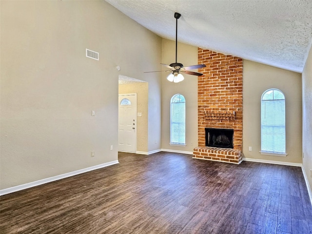 16502 Royal Mile Ln, Houston, TX 77084 - unfurnished living room with a textured ceiling, dark wood finished floors, ceiling fan, a brick fireplace, and high vaulted ceiling