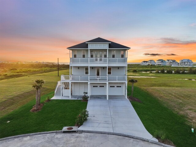 21330 Scissor Tail Ln, Galveston, TX 77554 - coastal home featuring a balcony, concrete driveway, a lawn, an attached garage, and stairs