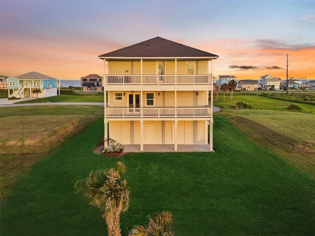 21330 Scissor Tail Ln, Galveston, TX 77554 - back of property at dusk with a patio, a lawn, a balcony, and roof with shingles