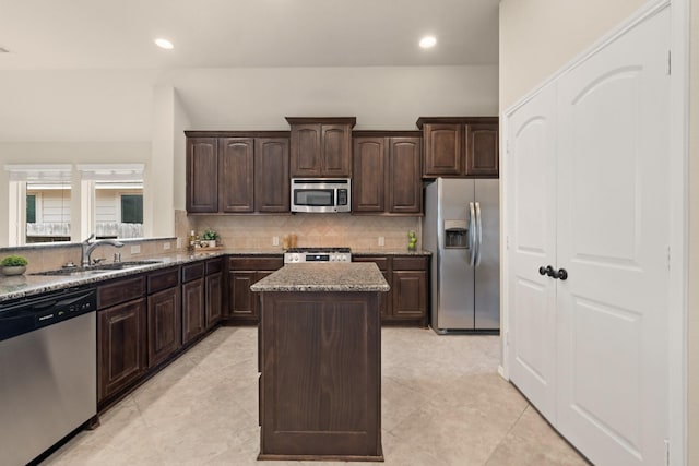 4211 Ponderosa Hills Ln, Katy, TX 77494 - kitchen featuring stainless steel appliances, a center island, tasteful backsplash, dark brown cabinets, and light stone countertops