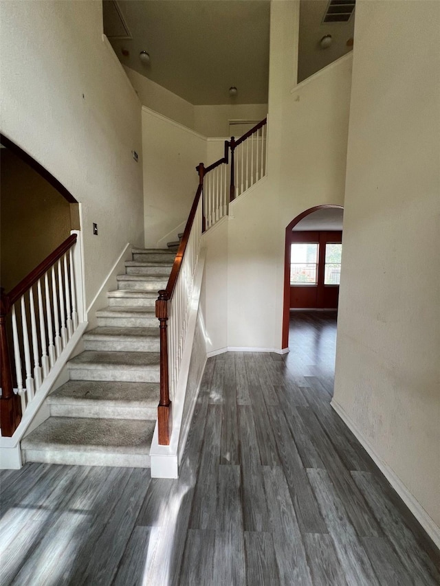 20019 Sterling Meadow Ct, Katy, TX 77449 - staircase with arched walkways, wood finished floors, and a high ceiling