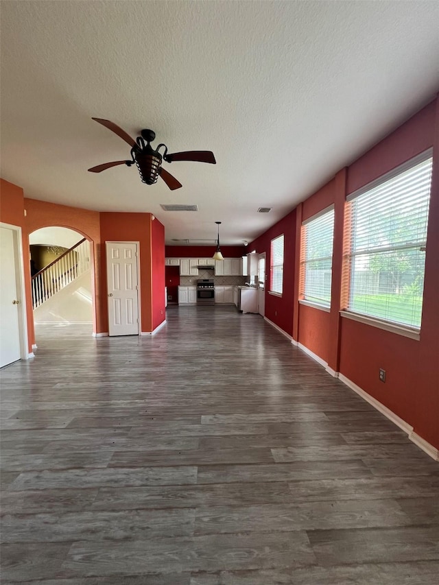 20019 Sterling Meadow Ct, Katy, TX 77449 - unfurnished living room with a ceiling fan, dark wood-type flooring, arched walkways, and a textured ceiling