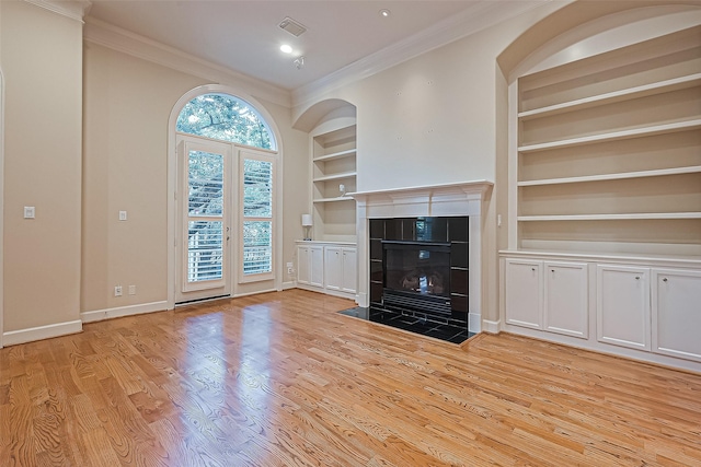2616 Helena St, Houston, TX 77006 - unfurnished living room featuring built in shelves, wood finished floors, ornamental molding, a tiled fireplace, and recessed lighting