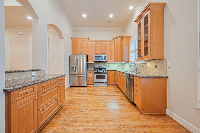 2616 Helena St, Houston, TX 77006 - kitchen featuring appliances with stainless steel finishes, arched walkways, ornamental molding, light wood finished floors, and dark stone countertops