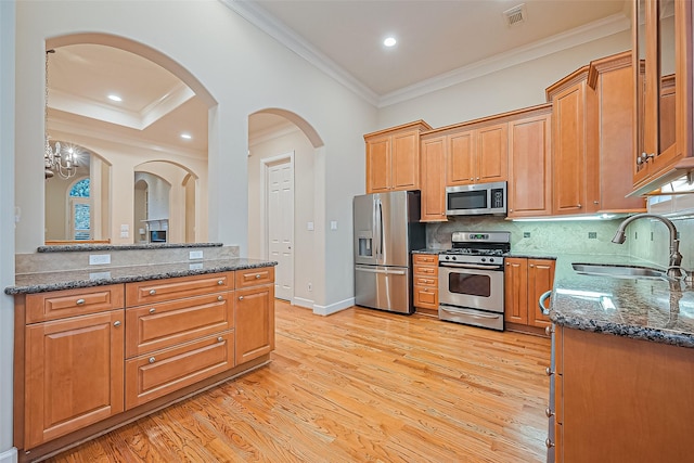 2616 Helena St, Houston, TX 77006 - kitchen featuring stainless steel appliances, crown molding, dark stone counters, light wood-style flooring, and decorative backsplash