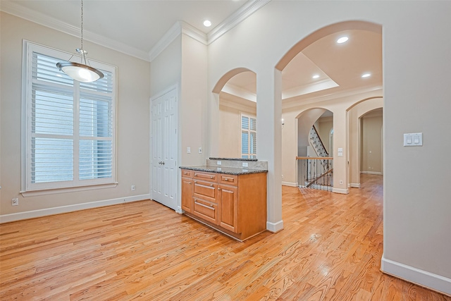 2616 Helena St, Houston, TX 77006 - kitchen with ornamental molding, arched walkways, brown cabinets, dark stone counters, and light wood finished floors