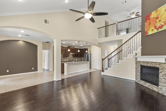 5314 Belle Manor Ln, Sugar Land, TX 77479 - unfurnished living room featuring ceiling fan, light wood-style flooring, high vaulted ceiling, arched walkways, and a fireplace