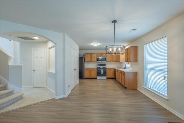 6511 Harcourt Bridge Dr, Houston, TX 77084 - kitchen featuring range, stainless steel microwave, freestanding refrigerator, arched walkways, and light countertops