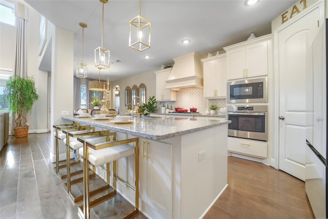 13526 Wedgewood Thicket Way, Cypress, TX 77429 - kitchen featuring appliances with stainless steel finishes, premium range hood, decorative backsplash, recessed lighting, and a center island with sink