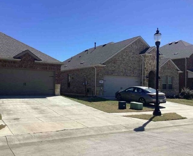 2920 Brady Starr Dr, Aubrey, TX 76227 - view of front of property featuring concrete driveway, a garage, roof with shingles, and stone siding