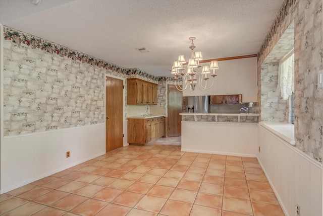414 Daffodil St, Lake Jackson, TX 77566 - kitchen with stainless steel fridge, a chandelier, light countertops, a textured ceiling, and a wainscoted wall