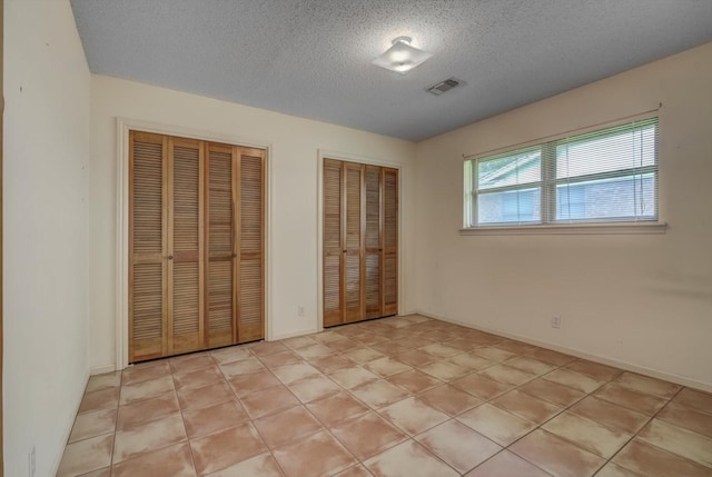 414 Daffodil St, Lake Jackson, TX 77566 - unfurnished bedroom featuring two closets and a textured ceiling