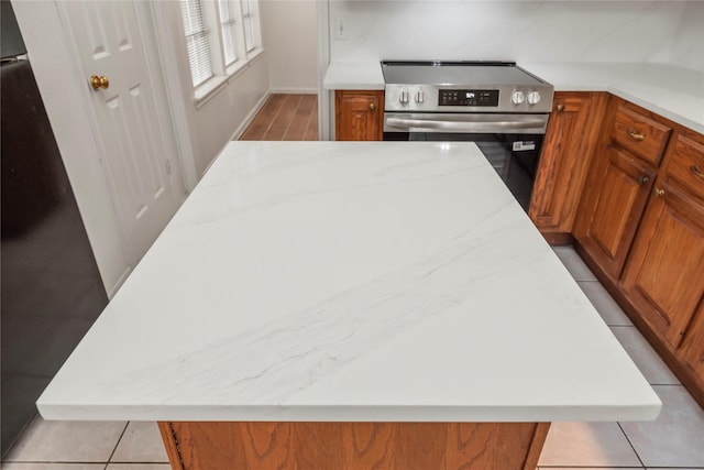 7331 Hazel Cove Dr, Houston, TX 77095 - kitchen with stainless steel electric stove, brown cabinetry, a large island, and light stone countertops