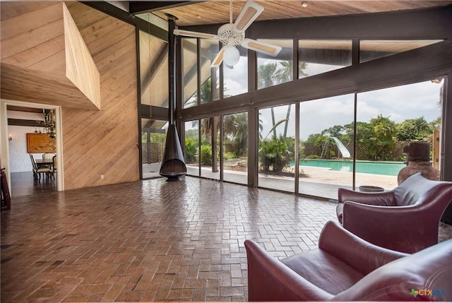 1809 W Harrison Ave, Port O Connor, TX 77982 - living area with wooden walls, a ceiling fan, brick flooring, beamed ceiling, and a towering ceiling