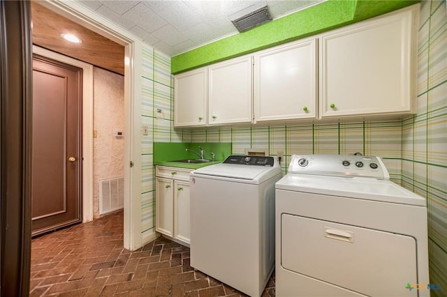 1809 W Harrison Ave, Port O Connor, TX 77982 - laundry room with cabinet space, brick floors, and washing machine and dryer