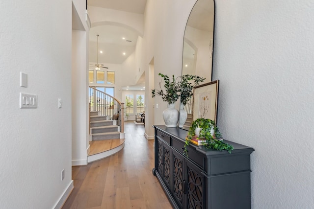 21514 Sunny Riverbank Cir, Cypress, TX 77433 - corridor with light wood-type flooring, stairway, arched walkways, a towering ceiling, and recessed lighting