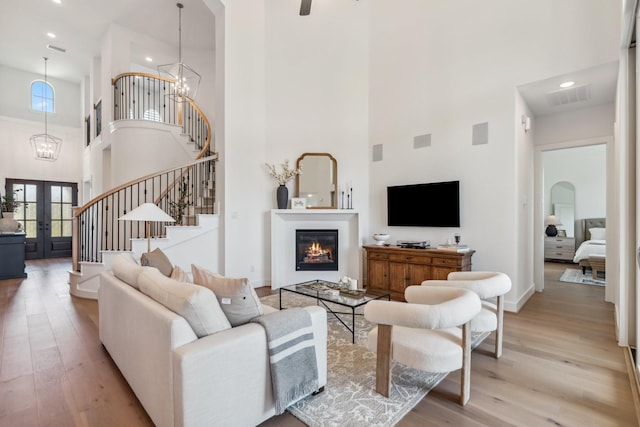 21514 Sunny Riverbank Cir, Cypress, TX 77433 - living room with a towering ceiling, light wood-style flooring, stairway, french doors, and a chandelier