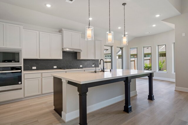 916 Wormwood Dr, League City, TX 77573 - kitchen with stainless steel appliances, tasteful backsplash, light countertops, a center island with sink, and white cabinets