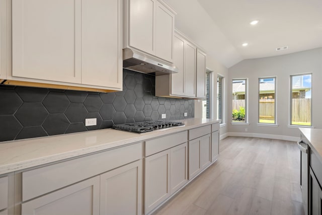 916 Wormwood Dr, League City, TX 77573 - kitchen with under cabinet range hood, appliances with stainless steel finishes, decorative backsplash, light wood-style floors, and lofted ceiling