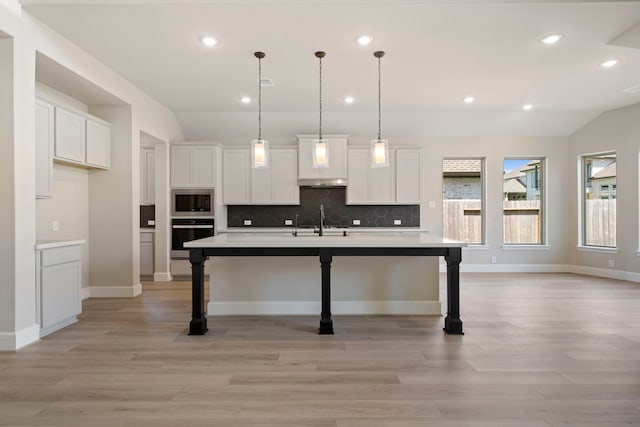 916 Wormwood Dr, League City, TX 77573 - kitchen with oven, vaulted ceiling, built in microwave, under cabinet range hood, and light wood finished floors