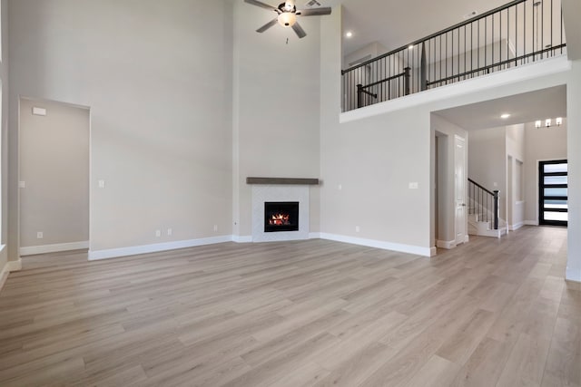 916 Wormwood Dr, League City, TX 77573 - unfurnished living room featuring a high ceiling, a ceiling fan, stairs, wood finished floors, and a fireplace