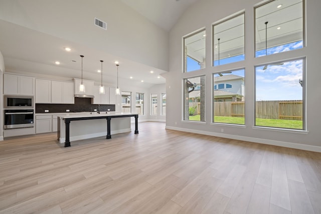 916 Wormwood Dr, League City, TX 77573 - kitchen with oven, built in microwave, open floor plan, white cabinetry, and a kitchen breakfast bar