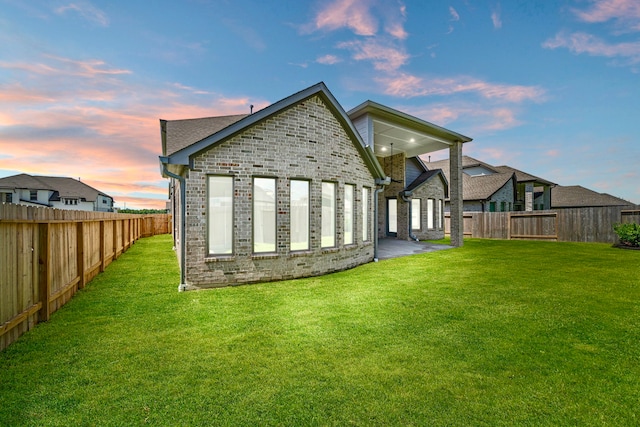 916 Wormwood Dr, League City, TX 77573 - back of property at dusk with brick siding, a fenced backyard, and a patio area