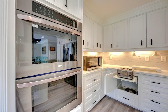 1950 Country Club Rd, Brenham, TX 77833 - kitchen with appliances with stainless steel finishes, white cabinetry, backsplash, and ornamental molding
